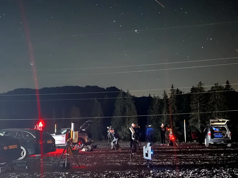 Astronomy community members observing together with telescopes under a starry mountain sky
